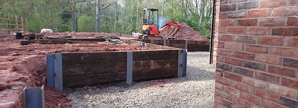 Timber sleeper raised beds and retaining beside a brick wall